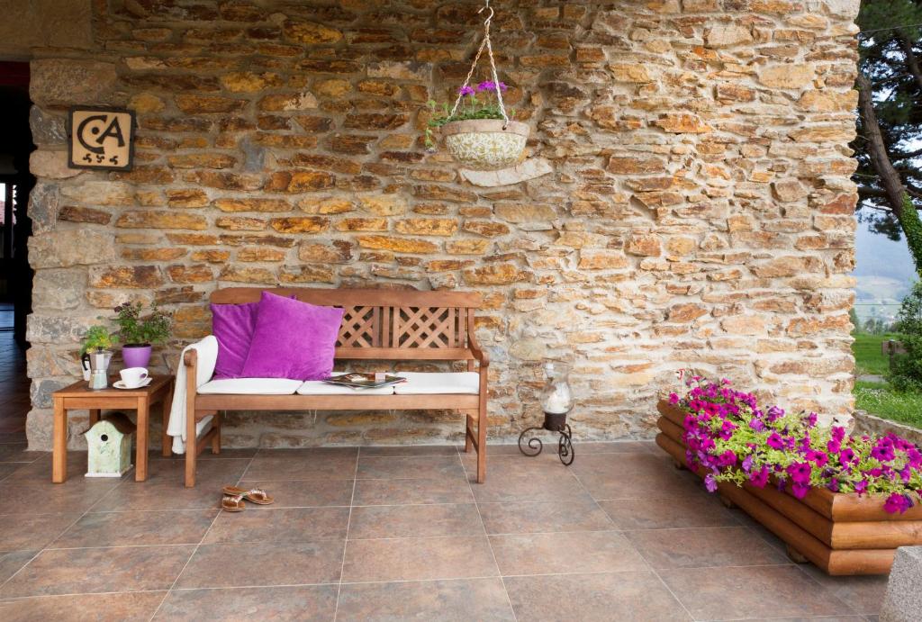 a patio with a chair and a table and a stone wall at La Casa de la Abuela Milagros in Pravia