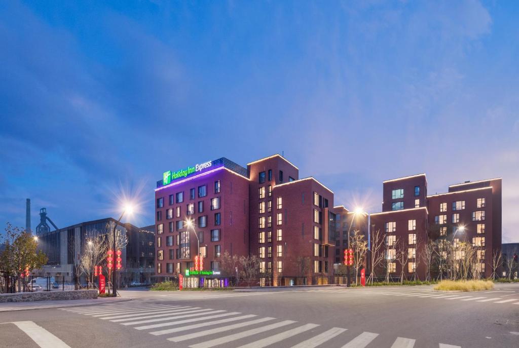 un edificio en la esquina de una calle por la noche en Holiday Inn Express Beijing Shijingshan Lakeview, an IHG Hotel, en Beijing