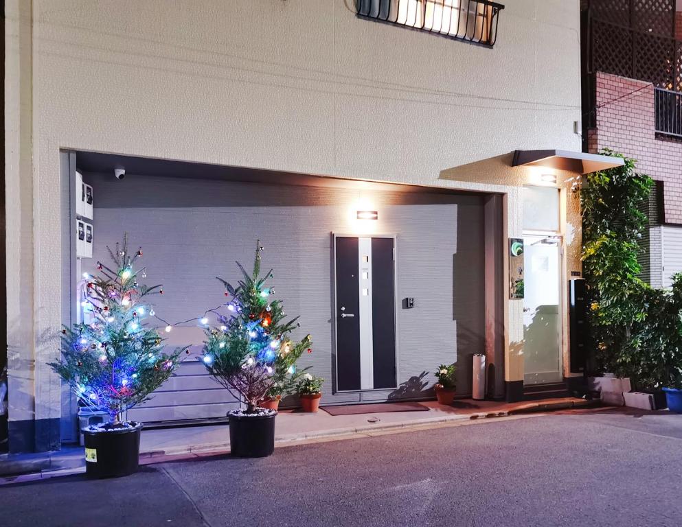 two christmas trees in pots in front of a garage at Mitsuba Guest House in Tokyo
