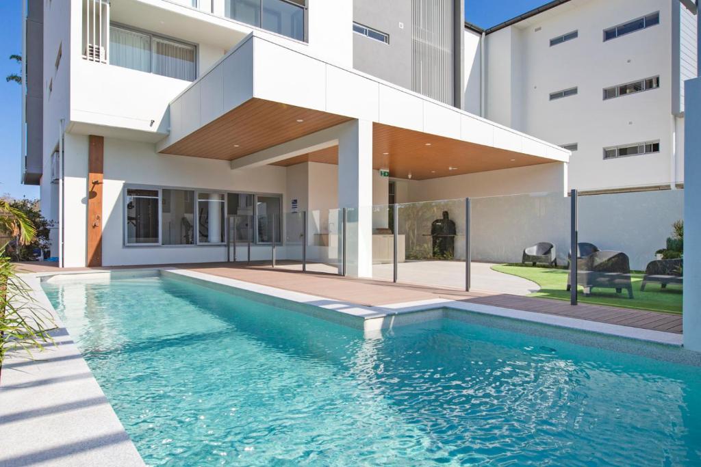 a swimming pool in front of a house at Dune Beachfront Apartments by Kingscliff Accommodation in Kingscliff
