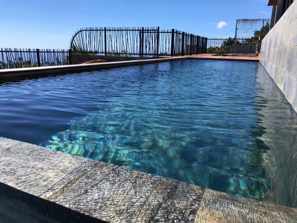 聖魯的住宿－OCEAN SUNSET，蓝色海水游泳池和围栏