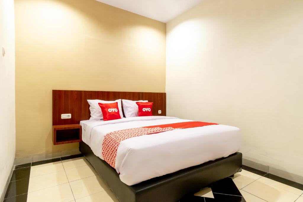 a bedroom with a large bed with red pillows at Capital O 1585 Ring Road Residence in Medan