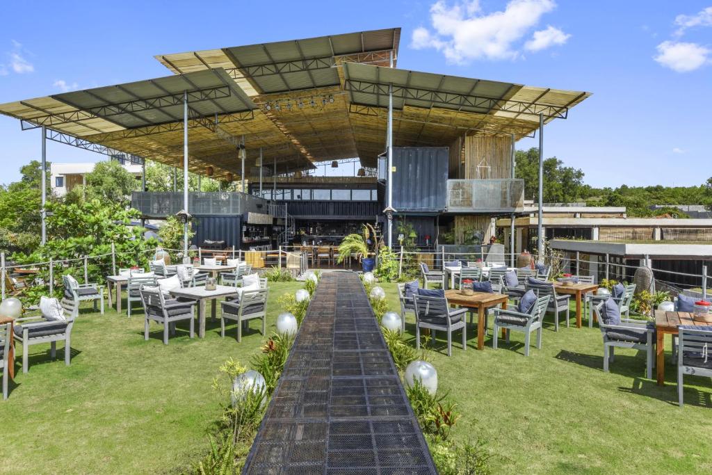a restaurant with tables and chairs on a lawn at Cargo Remote Mui Ne in Phan Thiet