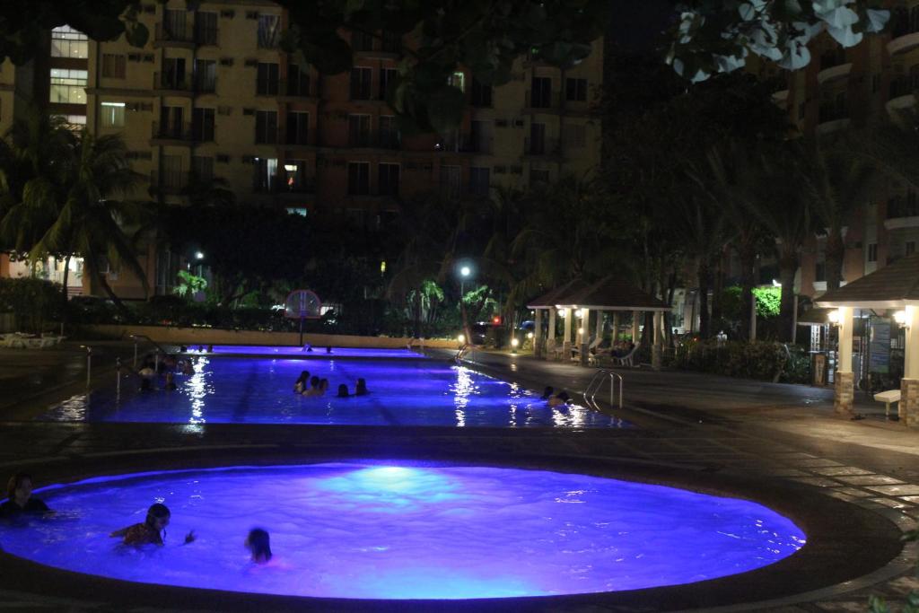 - une grande piscine bleue avec des personnes la nuit dans l'établissement CHATEAU ELYSEE a6 near AIRPORT Wifi Kitchen, à Manille