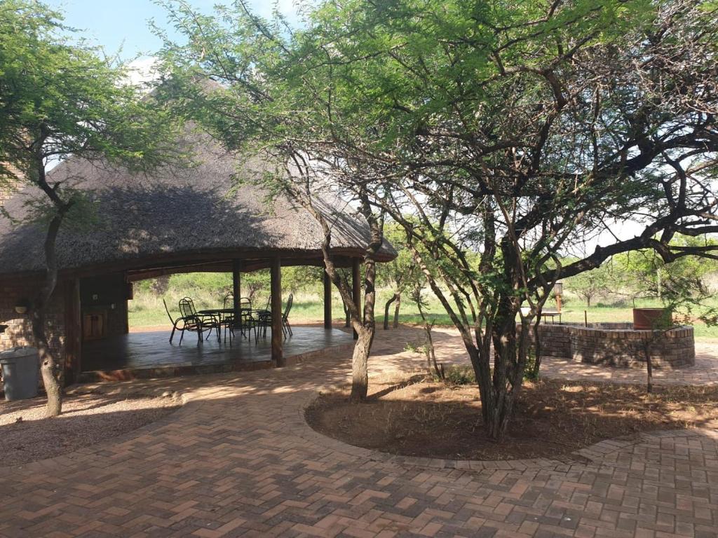 a pavilion with a picnic table and a tree at Makhato Bush Lodge 17 in Bela-Bela