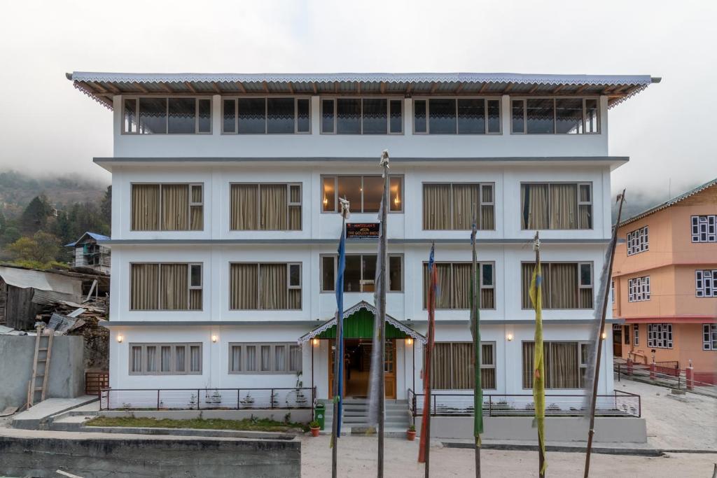 a white building with a basketball court in front of it at Magellan's The Golden Bridge in Lachung