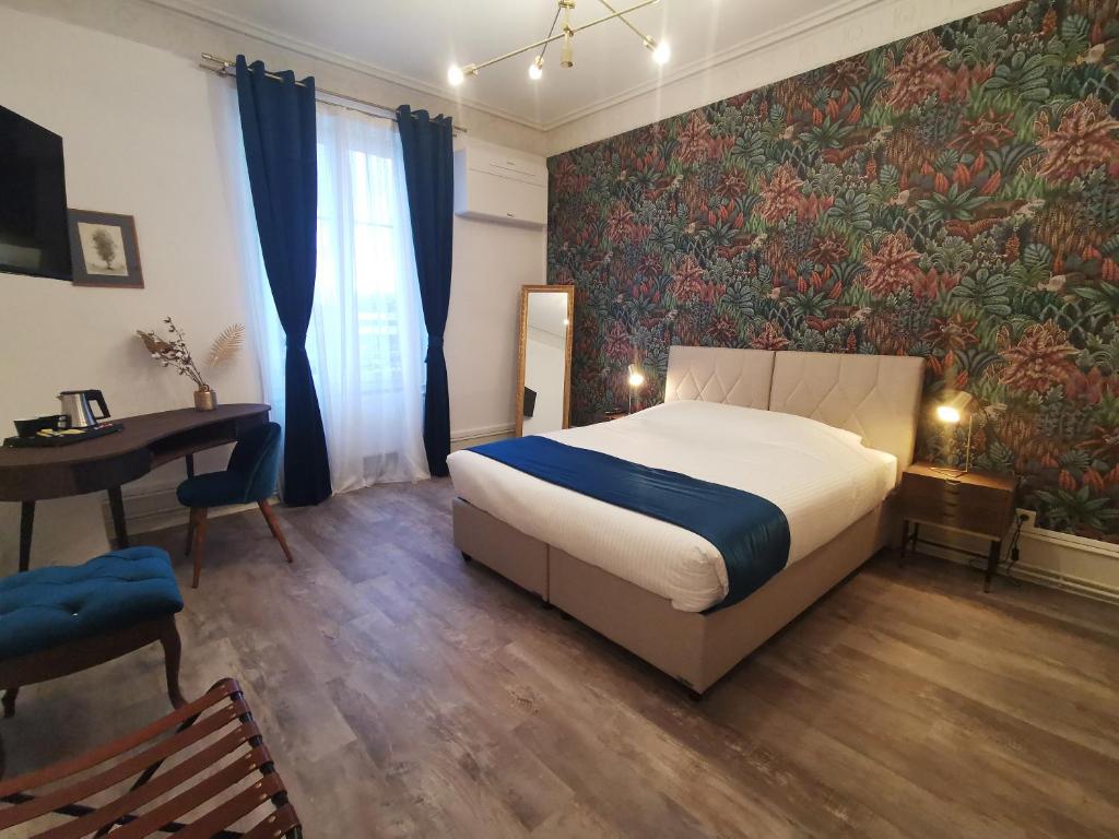 ein Schlafzimmer mit einem Bett, einem Schreibtisch und einem Wandbild in der Unterkunft Colmar Suites - Résidence in Colmar