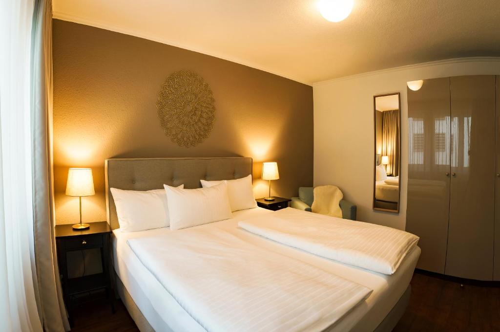 ein Schlafzimmer mit einem großen weißen Bett mit zwei Lampen in der Unterkunft Hotel Rappen am Münsterplatz in Freiburg im Breisgau