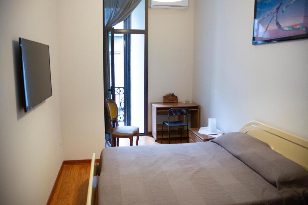 um quarto com uma cama, uma escrivaninha e uma televisão em Relax in Centro em Nápoles
