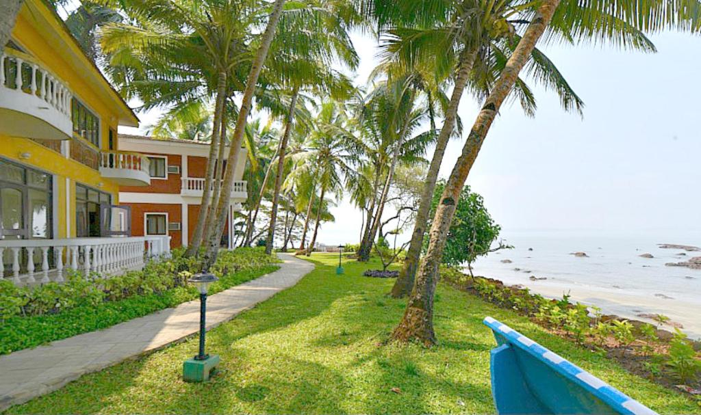 a house with palm trees next to the ocean at Bambolim Beach Resort in Bambolim