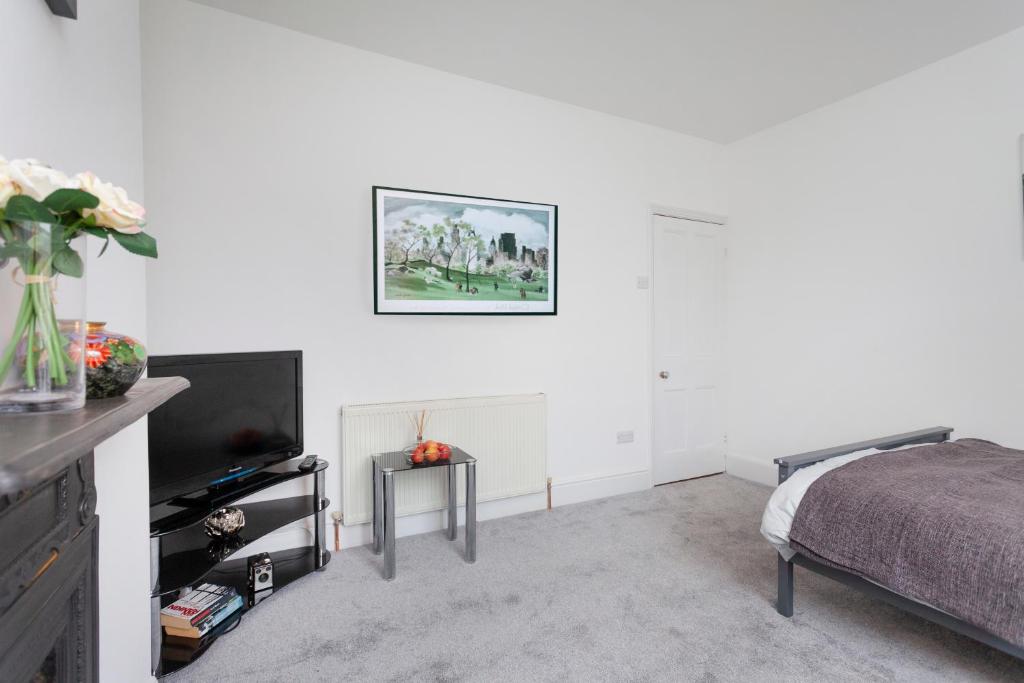 a white bedroom with a bed and a tv at Clarendon in Leicester