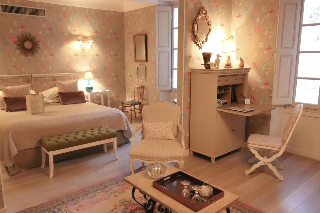 a bedroom with a bed and a table and chairs at La Maison du Frene in Vence