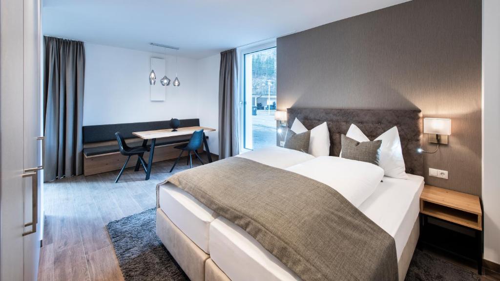 a hotel room with a large bed and a desk at MANNI village - lifestyle apartments in Mayrhofen
