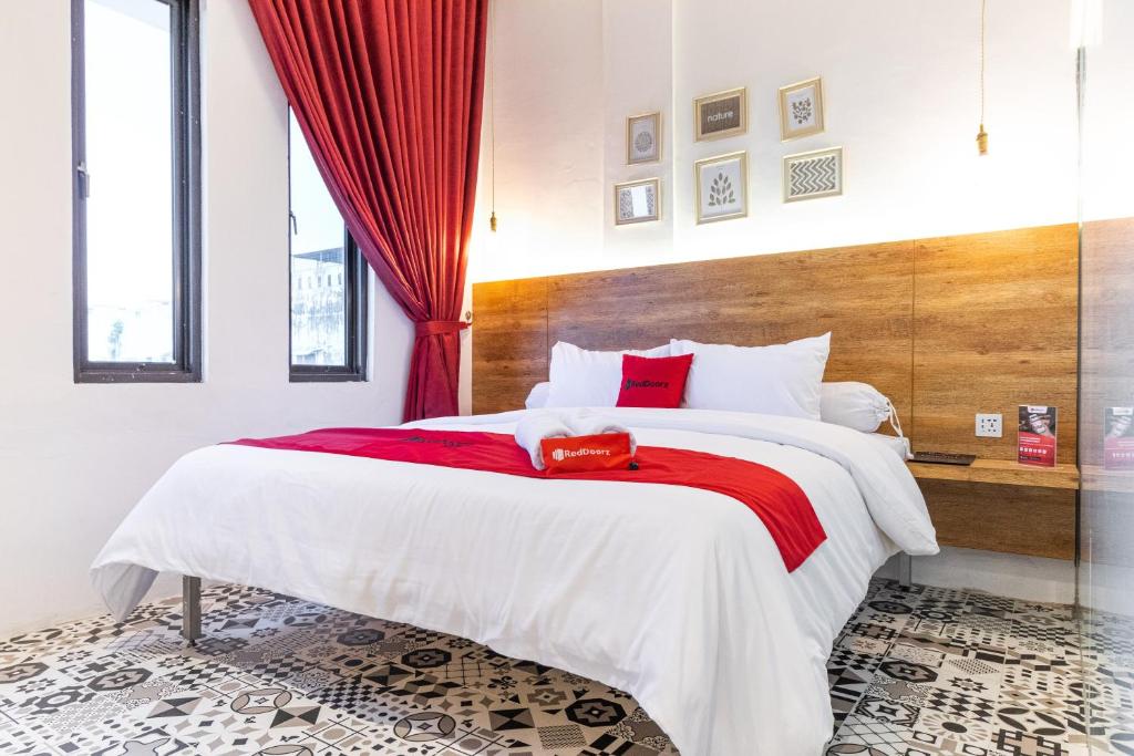a bedroom with a large white bed with red accents at RedDoorz Plus At Mitrotel Medan in Sunggal