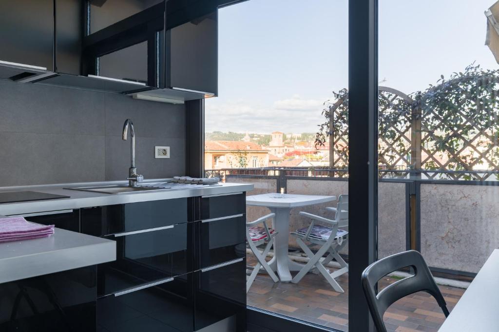 Il comprend une cuisine avec des armoires noires et un balcon avec une table. dans l'établissement Central Apartment Behind the Arena, à Vérone