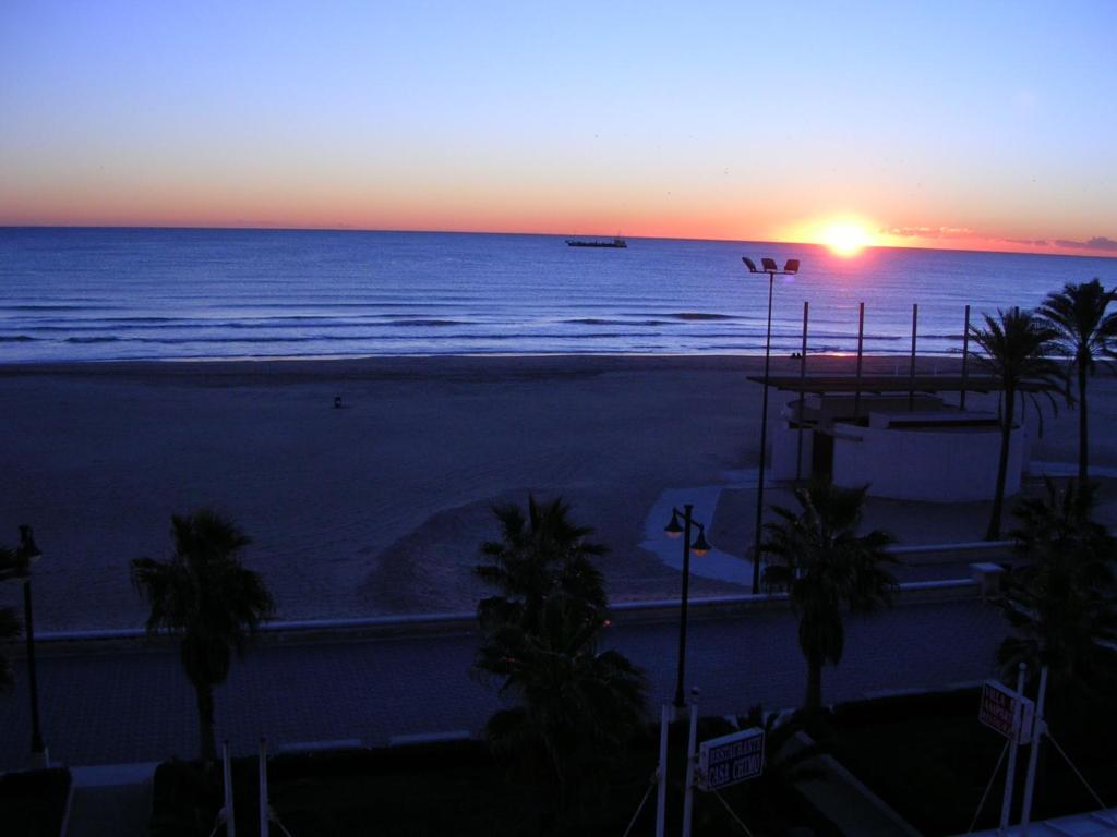 una puesta de sol sobre una playa con palmeras y el océano en El Globo, en Valencia
