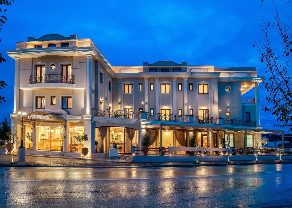 a large white building at night at Olympus Terra Boutique Hotel in Larisa