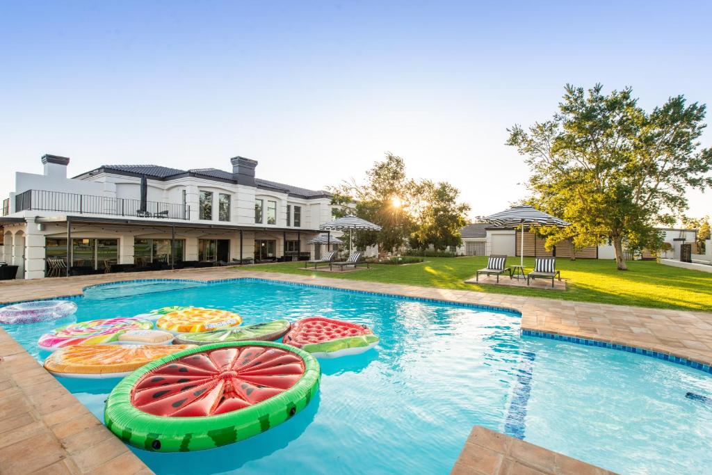 a pool with inflatables in the water in front of a house at The Feather Hill Boutique Hotel in Potchefstroom