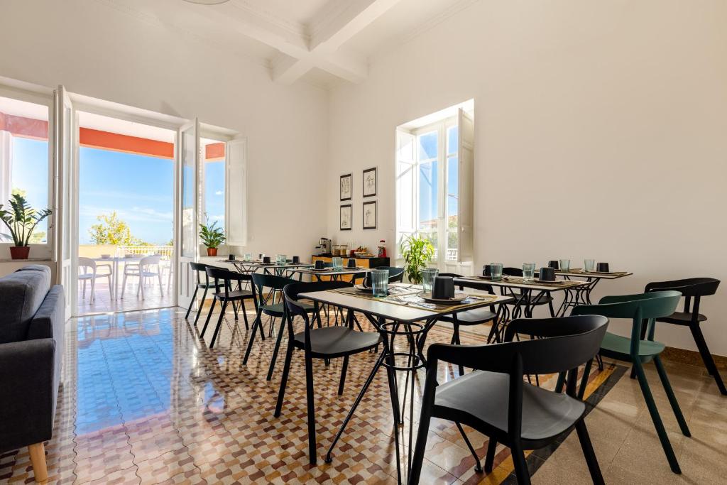 a dining room with tables and chairs and windows at Villa Edera Rental Room in Santa Flavia