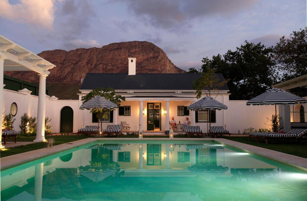 a house with a swimming pool in front of a mountain at La Cotte The Manor House in Franschhoek