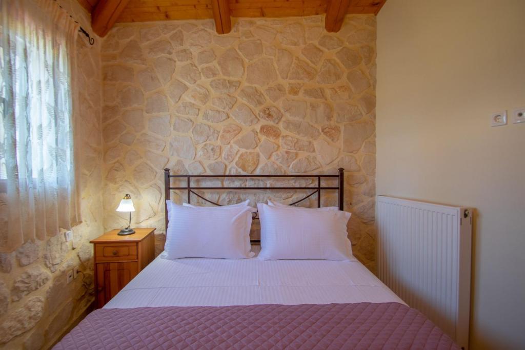 a bedroom with a bed and a stone wall at Kantouni House in Volimes