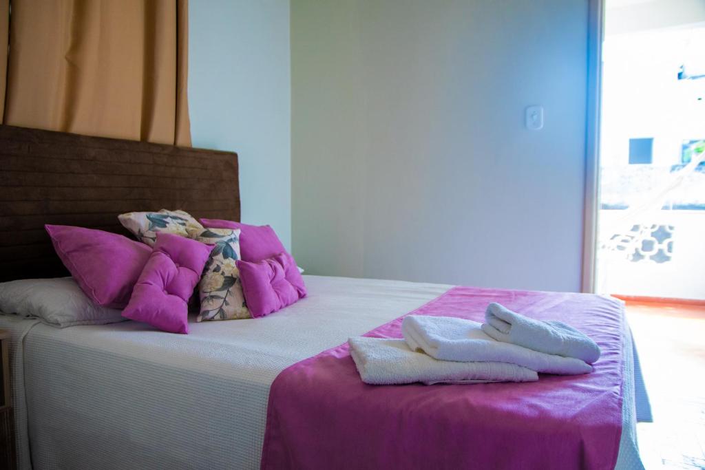 a bed with purple and white pillows and towels on it at Hotel Casa Branca in Uruguaiana