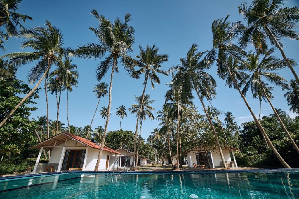 un complejo con una piscina con palmeras en el fondo en Simply Peace en Tangalle