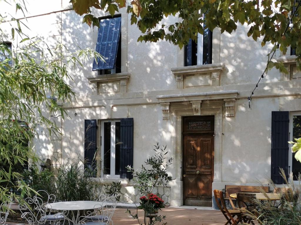 ein weißes Haus mit einer Holztür und einem Tisch in der Unterkunft Maison d' Alys entre Luberon et Alpilles in Cabannes