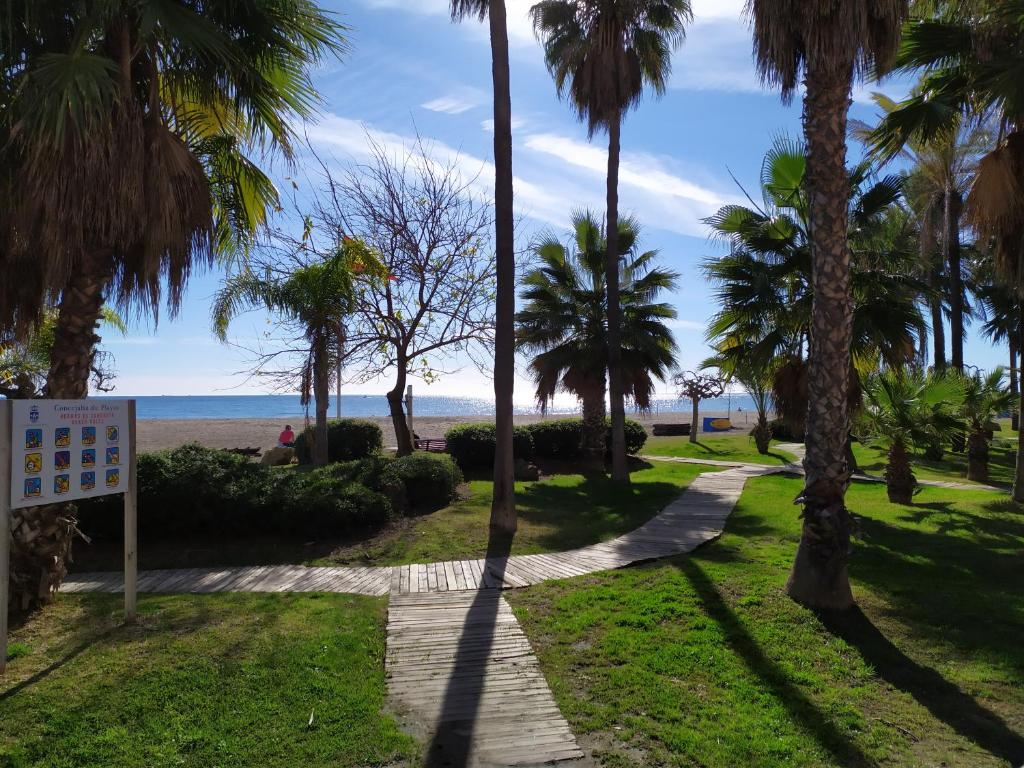 un camino que conduce a la playa con palmeras en Benalmádena Piscis Sun & Beach, en Benalmádena