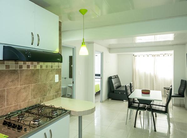 a kitchen and living room with a stove and a table at ApartaHotel Luxury in Paipa