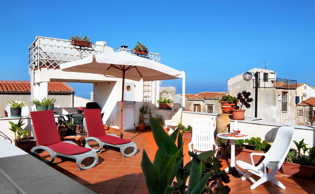 patio z krzesłami, parasolem i stołem w obiekcie Hotel La Giara w Cefalù
