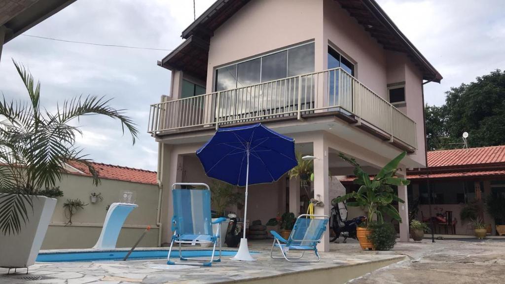 um grupo de cadeiras e um guarda-sol em frente a uma casa em CANTINHO DA PAZ! em Águas de São Pedro