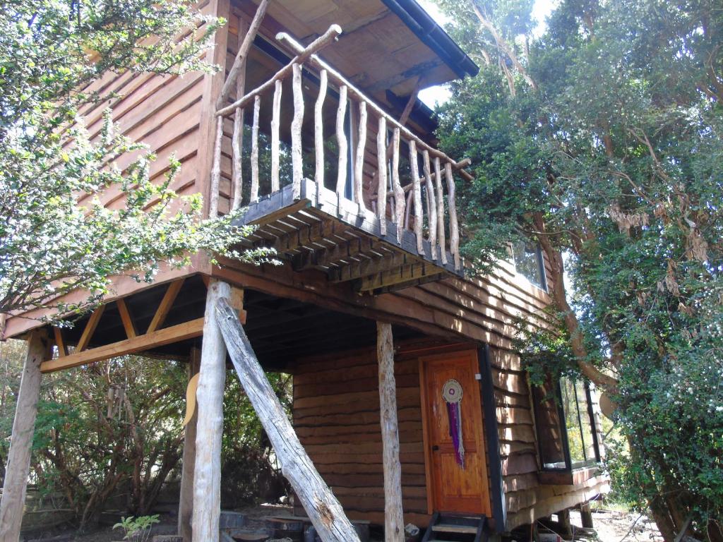een boomhut met een houten trap en een veranda bij La Ranchita de Queilen in Queilén