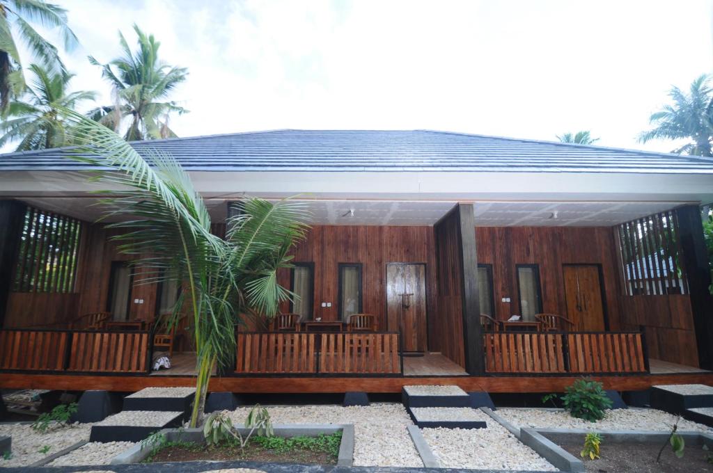 Sunari Beach Resort 2 في Selayar: منزل بألواح خشبية و نخلة