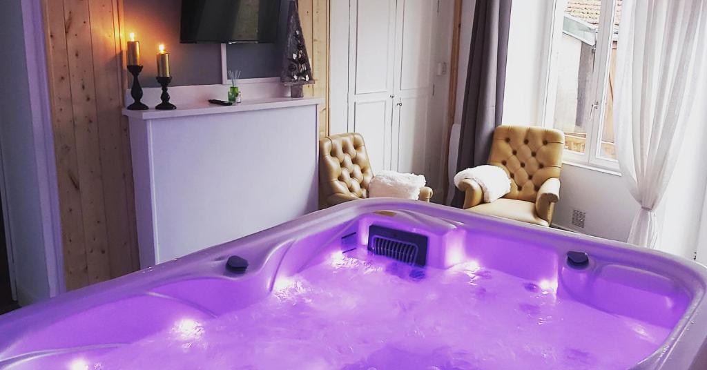 a purple tub in a room with two chairs at Suite EDEN avec jacuzzi privé in Chaumont