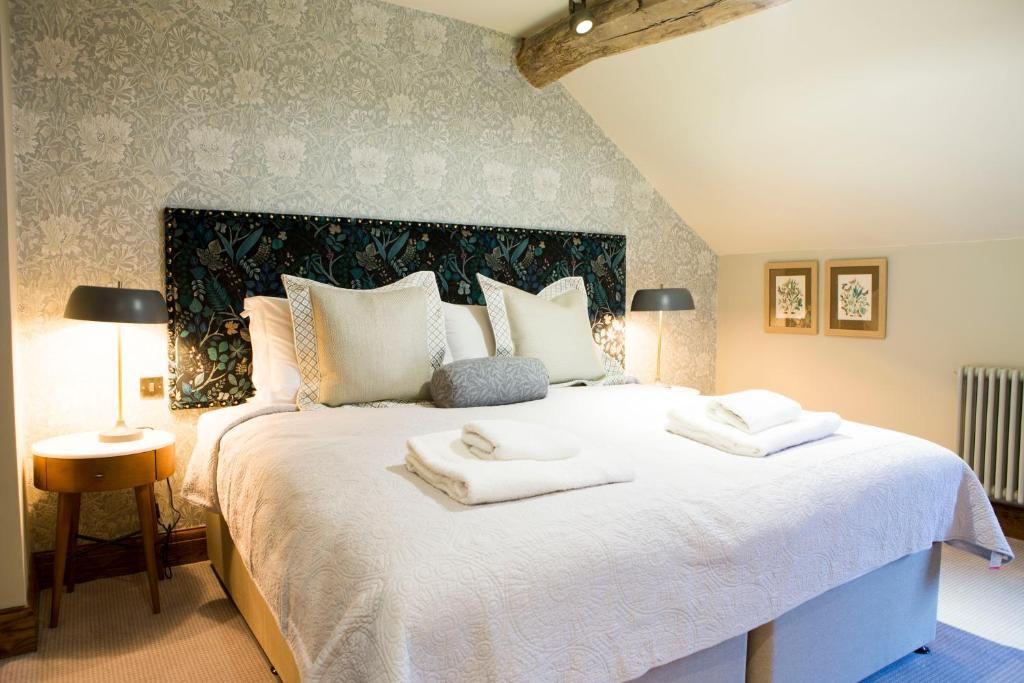 a bedroom with a large white bed with towels on it at The Legh Arms Prestbury in Macclesfield