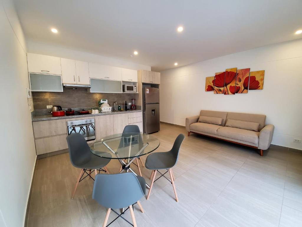 cocina y sala de estar con mesa de cristal y sillas en Nuevo Condominio en Ocean Reef, en San Bartolo