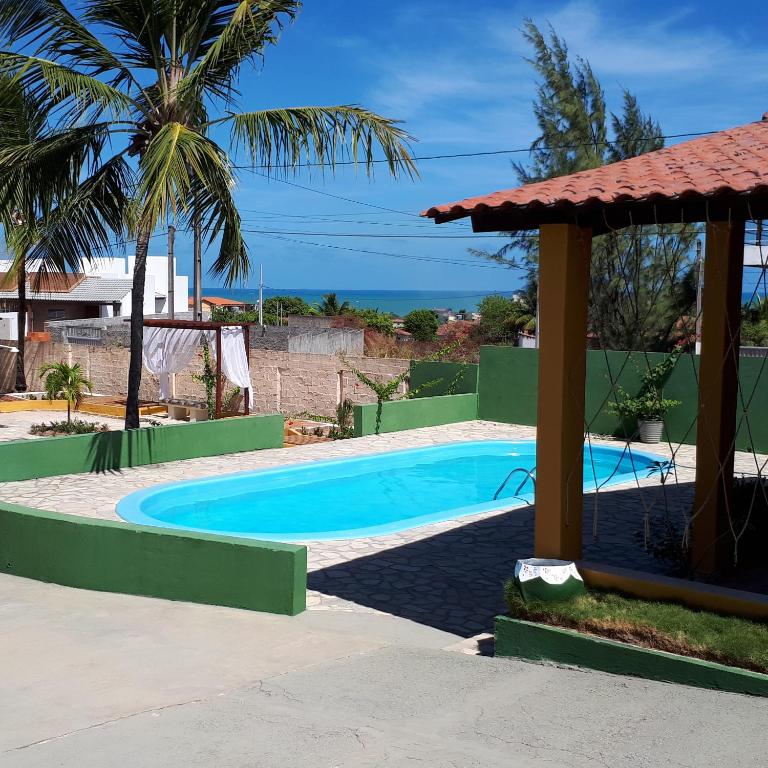 a swimming pool with a gazebo and the ocean at Pousada O Tabuleiro in Jacumã