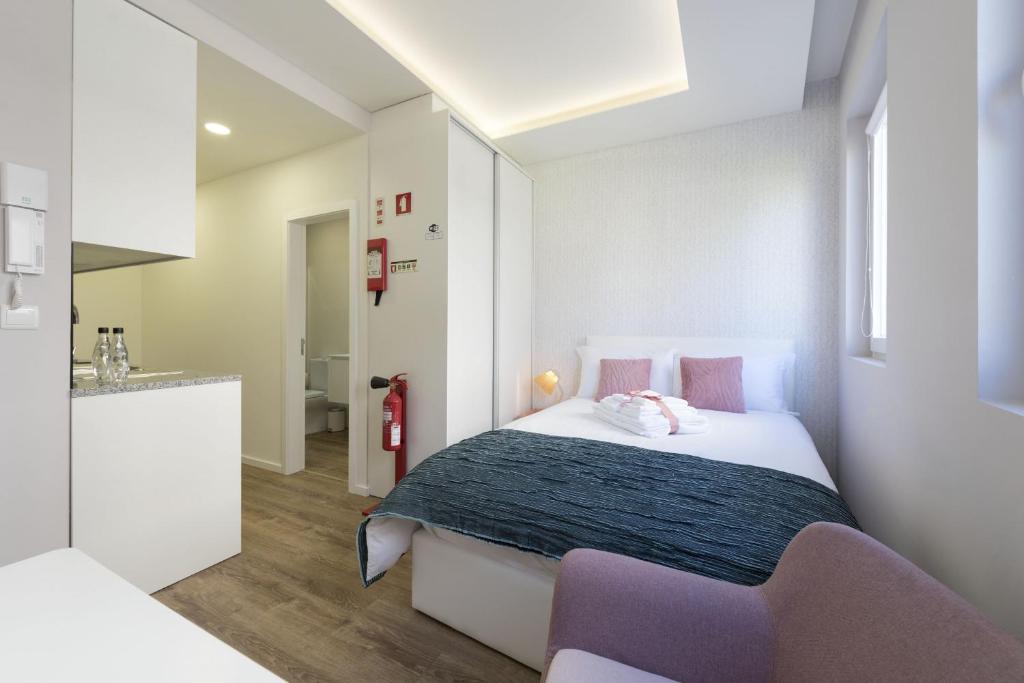 a small bedroom with a bed and a kitchen at Apartamentos do Prado In Douro in Vila Real