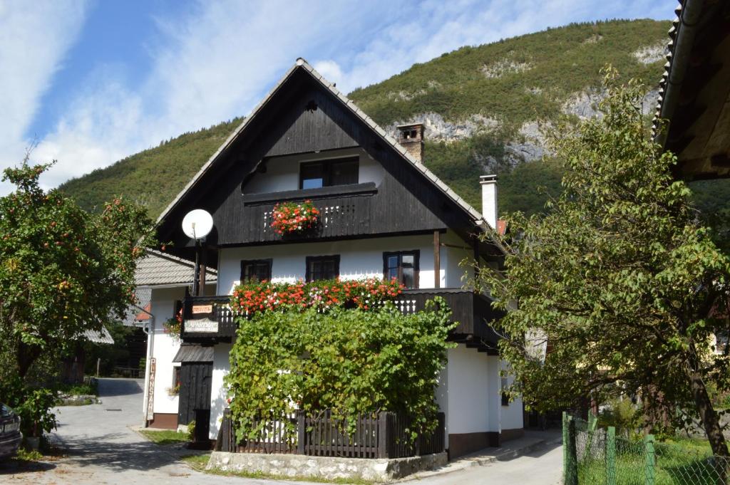 a house with a black roof and flowers on the balcony at Hiša Planšar Bohinj accommodations in Bohinj