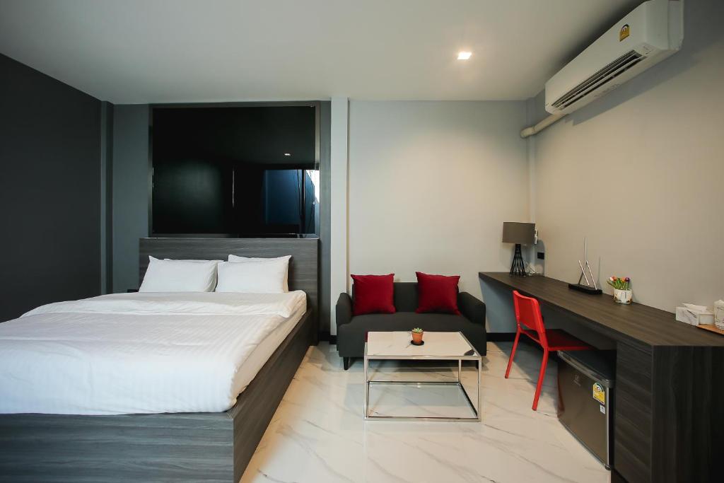una camera con letto, scrivania e divano di Grand Park Resort a Ban Chorakhe Bua