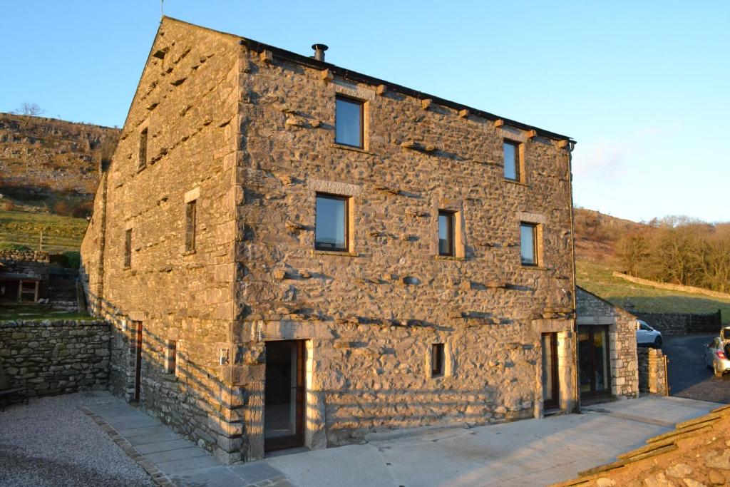 een oud stenen gebouw met een stenen muur bij Dalecote Barn Bed & Breakfast in Ingleton 