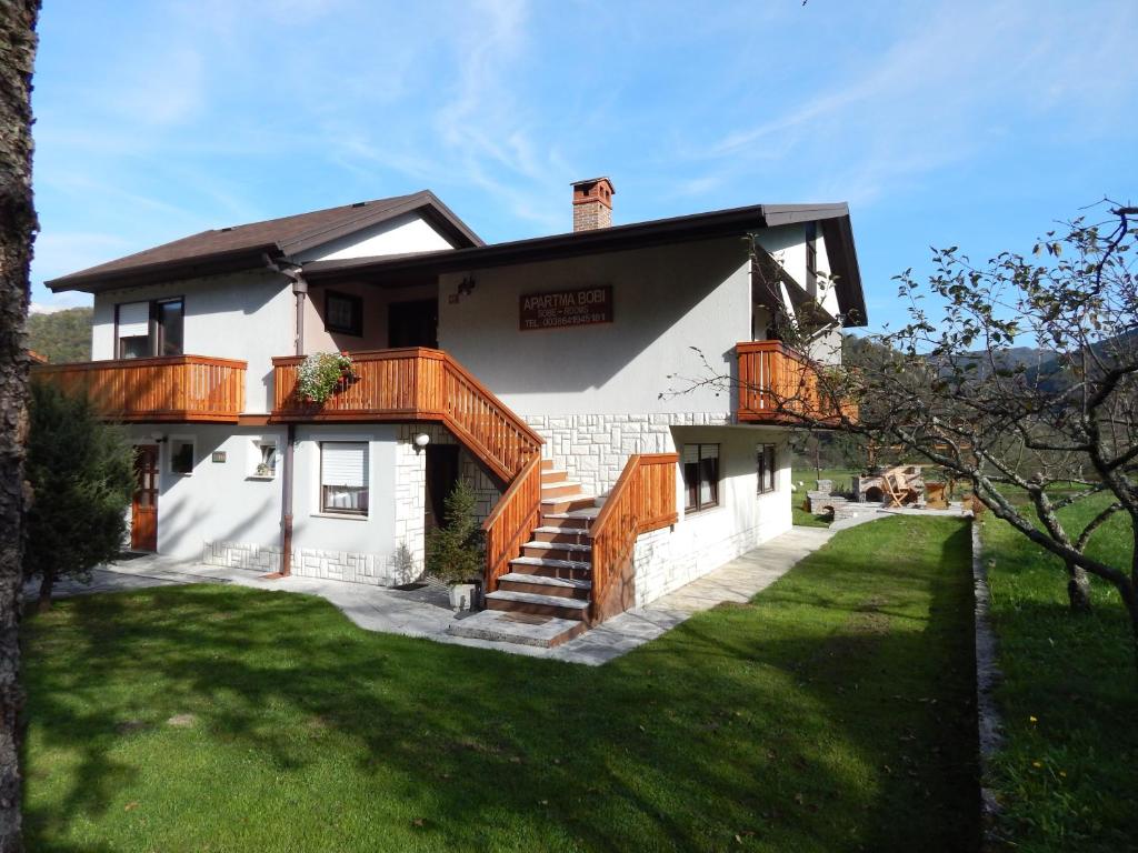 a white house with wooden decks and a yard at Apartments Bobi in Tolmin