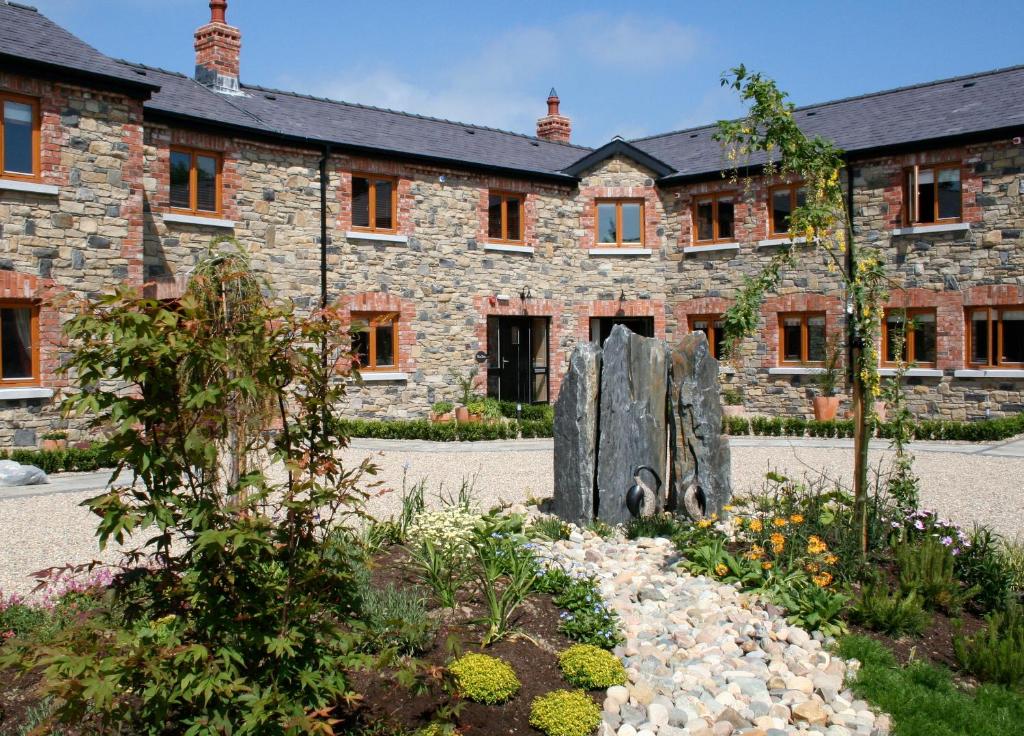 - un bâtiment en pierre avec une statue en face dans l'établissement Decoy Country Cottages, à Navan