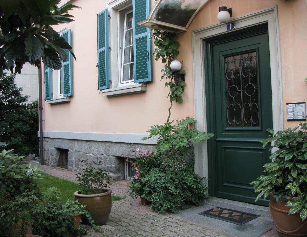 eine grüne Tür auf einem Haus mit Topfpflanzen in der Unterkunft Casa Jolanda in Bellinzona