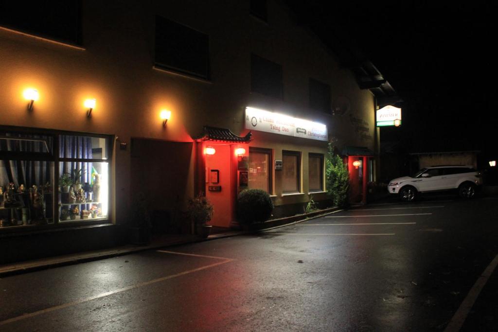 an empty parking lot in front of a building at night at Pension & Restaurant TsingDao in Hörbranz