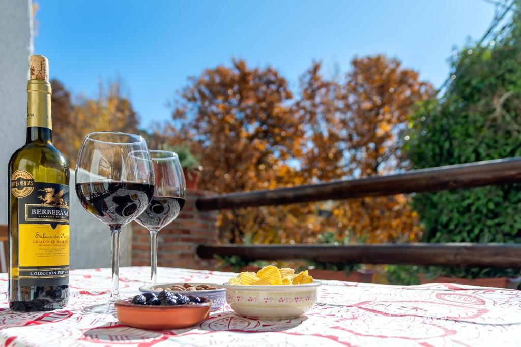 eine Flasche Wein und zwei Gläser auf dem Tisch in der Unterkunft Casa Consuelo in Capileira