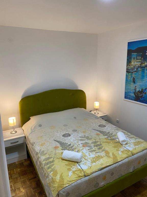 un lit avec une tête de lit verte et 2 tables de chevet dans l'établissement Apartment M, à Višegrad