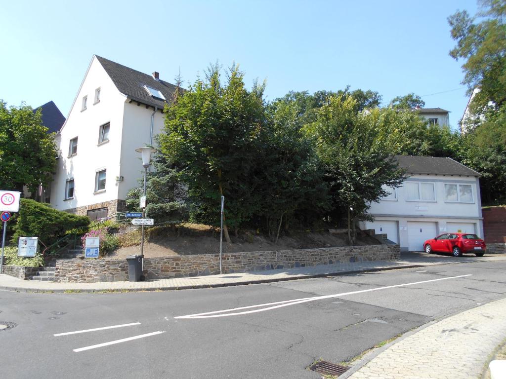 ein rotes Auto, das vor einem weißen Haus parkt in der Unterkunft Järgen Ferienappartements in Koblenz