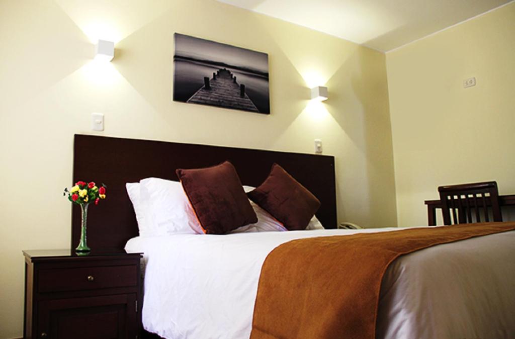1 dormitorio con 1 cama con sábanas y almohadas blancas en Hotel Ferrua, en Lima